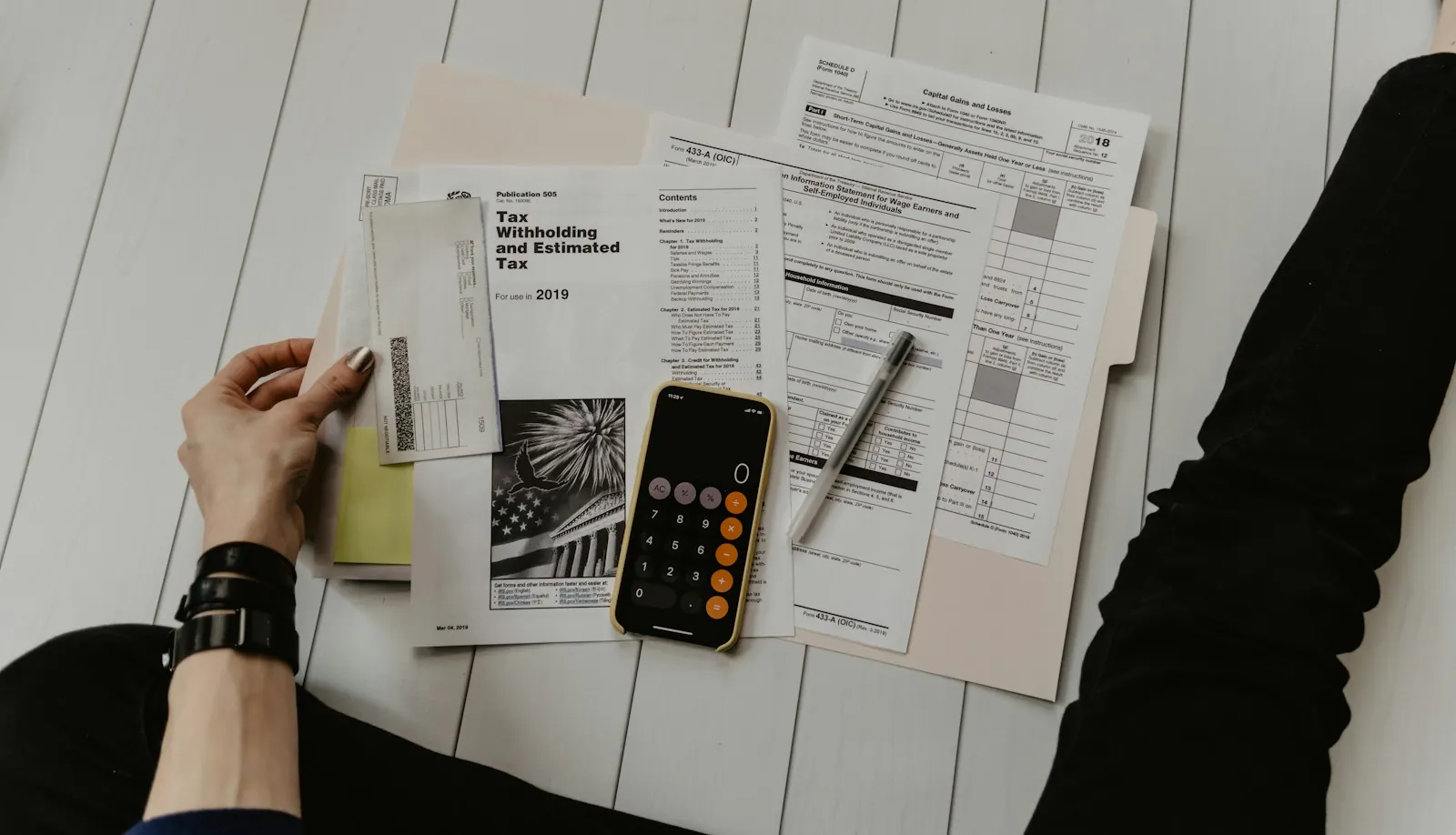 Person working through tax forms with a calculator and phone