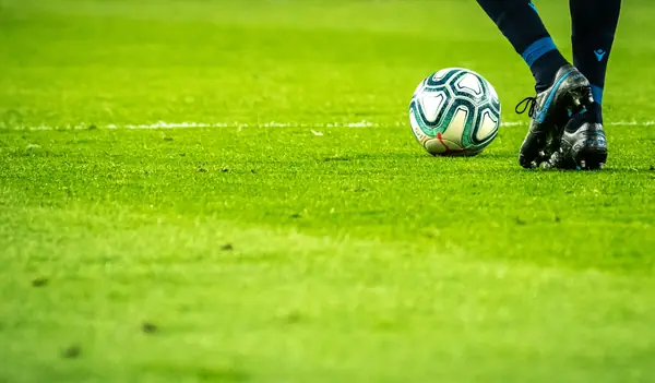 Football at a player's boot on a grass pitch